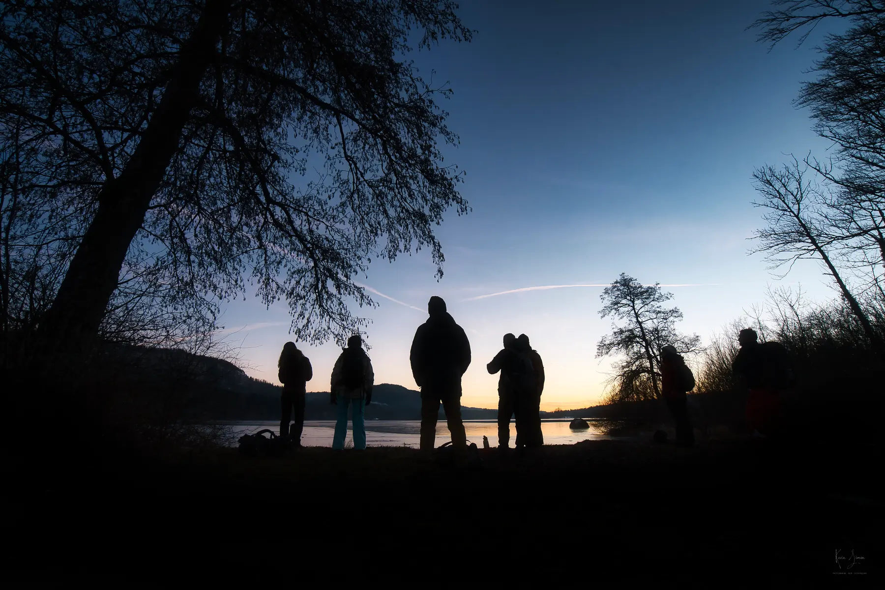 Des silhouettes au crépuscule au bord d’un lac