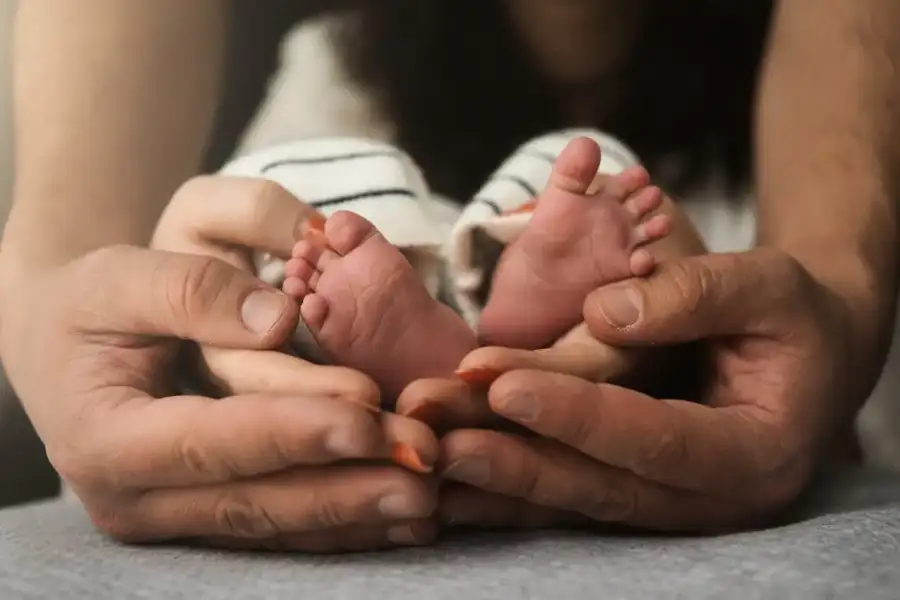 Les petits pieds d’un nouveau-né dans les mains de ses parents