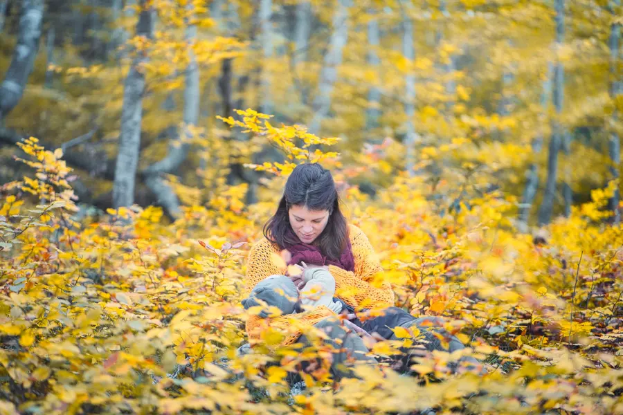Une femme lit, assise dans les feuilles d’automne