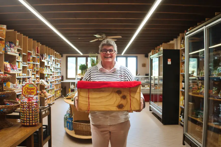 Une commerçante sourit, une caisse en bois dans les bras